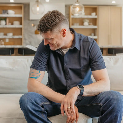 Man sitting on a couch and wearing a Signal Relief patch on his upper arm.